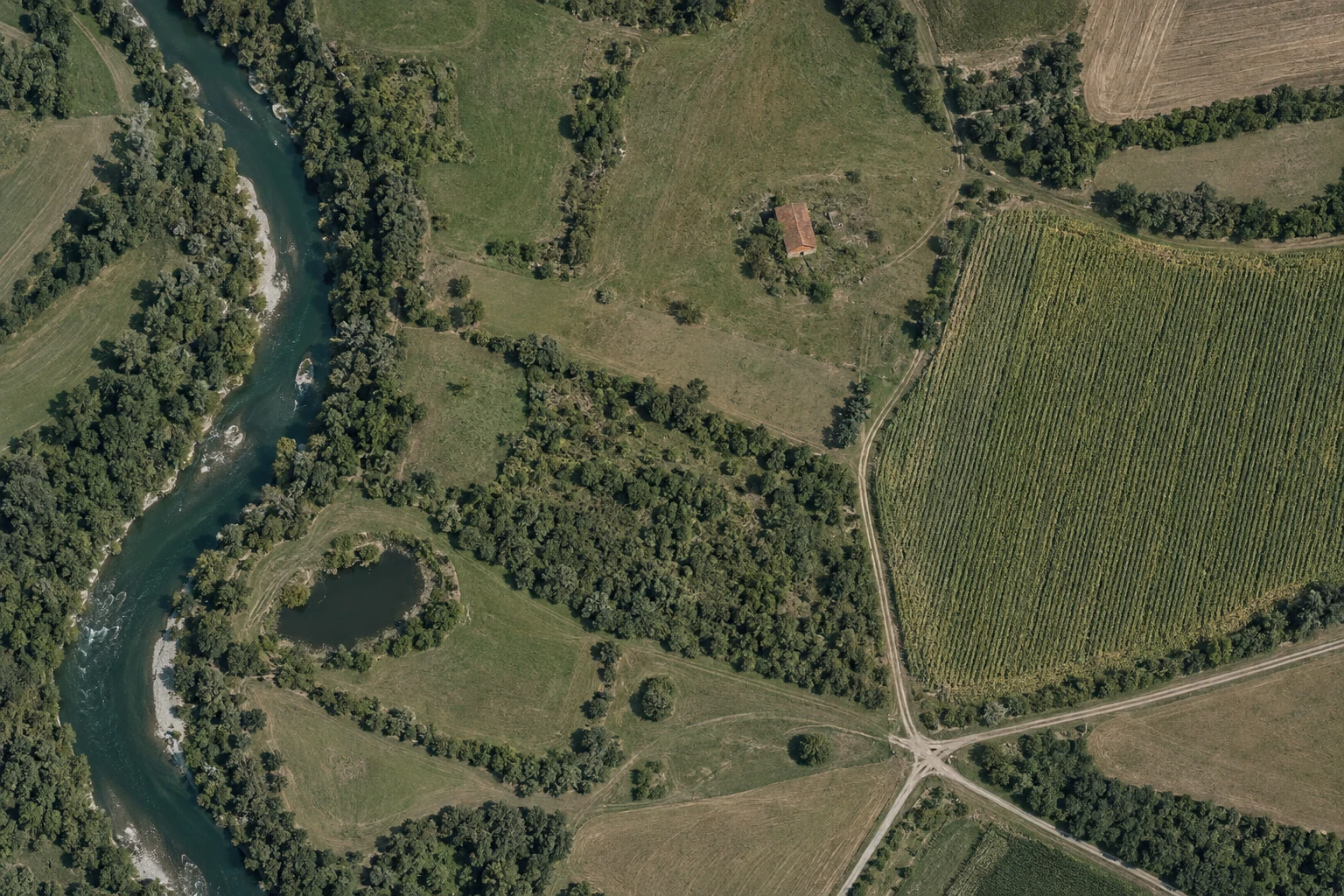 Szemléltető légi térkép folyóval, elhagyott épülettel, kukoricással és bokros területtel.